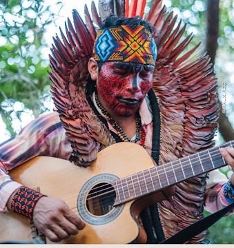 Txana Ibã playing guitar with traditional face paint